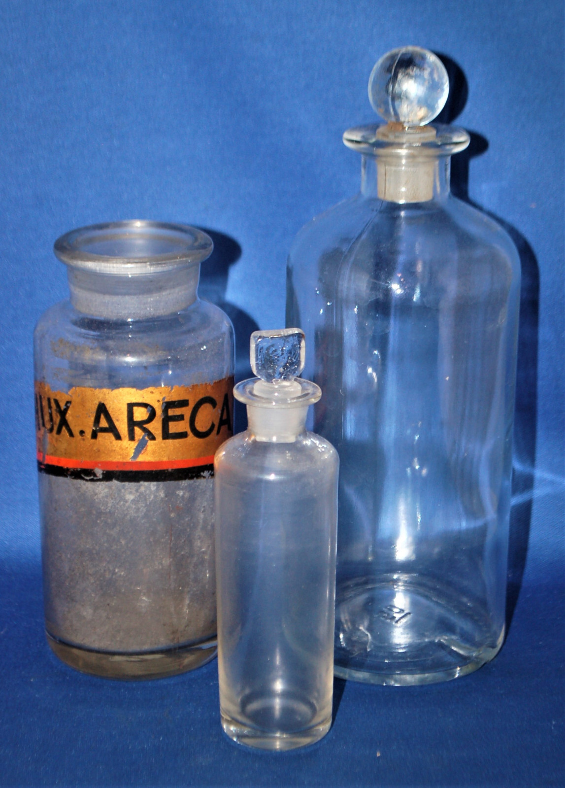 Three antique glass apothecary bottles, one with label, missing top