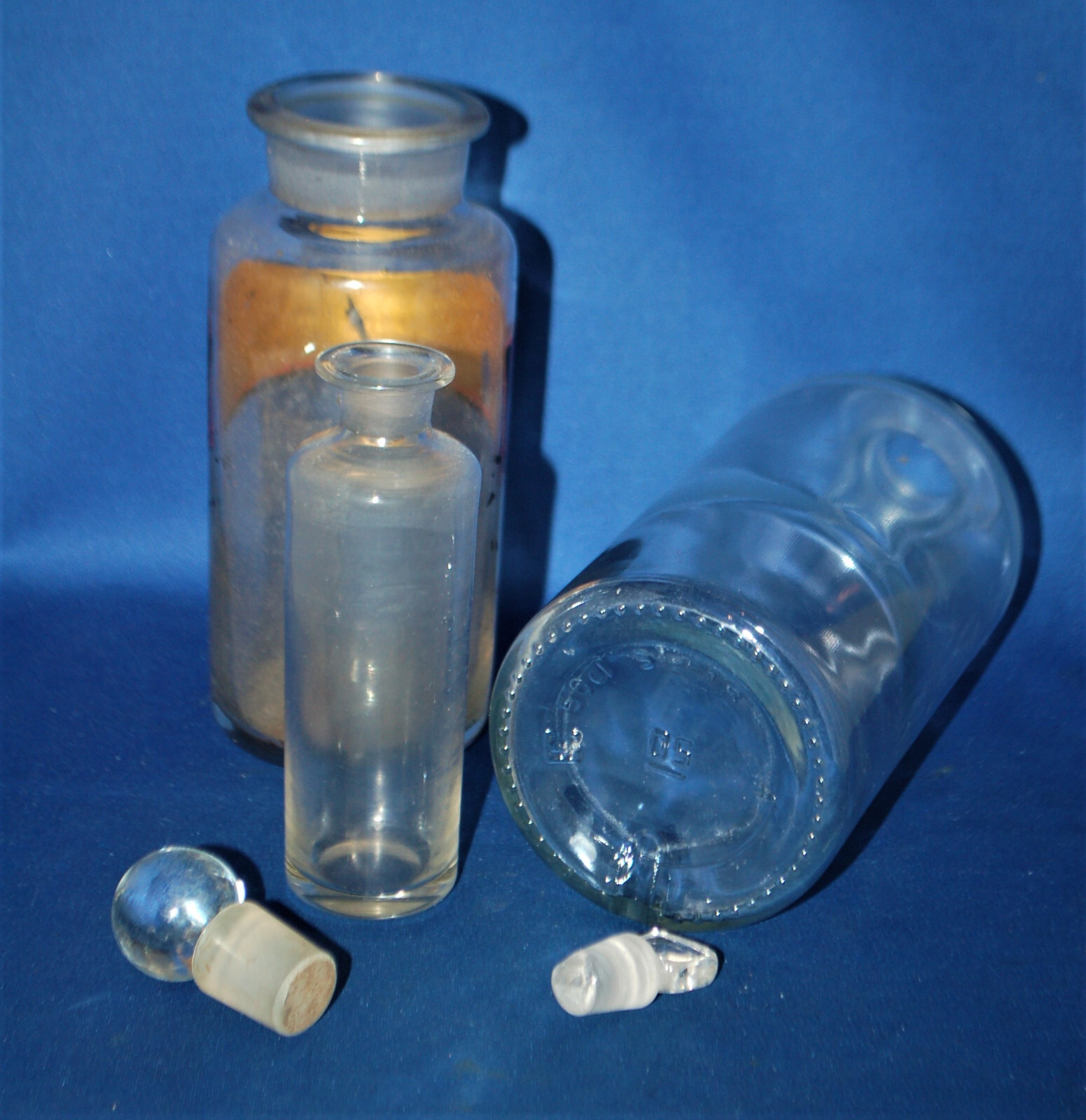 Three antique glass apothecary bottles, one with label, missing top